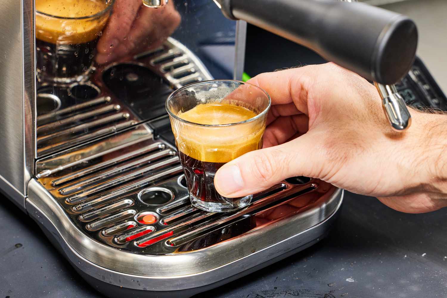 Hand holding freshly brewed espresso coffee on Breville Bambino Plus Espresso Machine tray