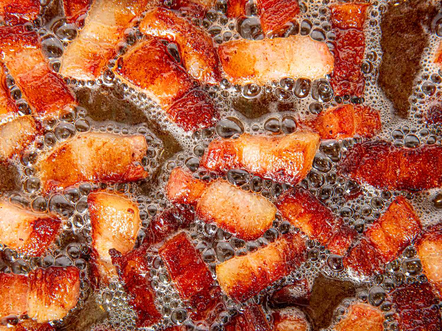 Overhead view of lardons cooking in skillet