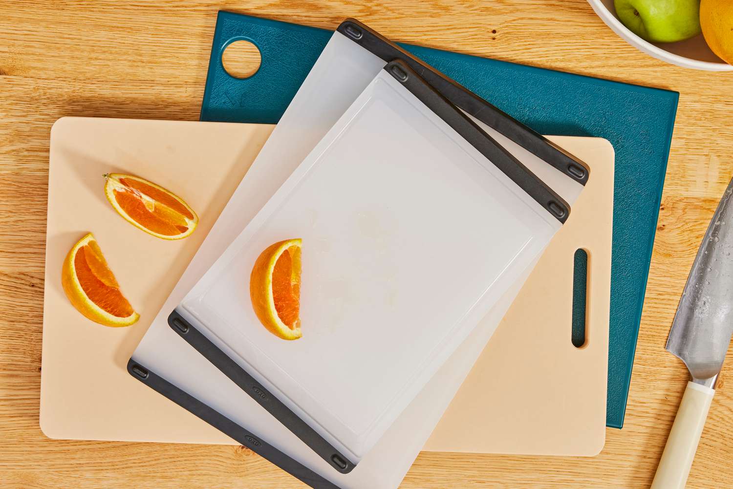 Three plastic cutting boards on a wooden countertop.