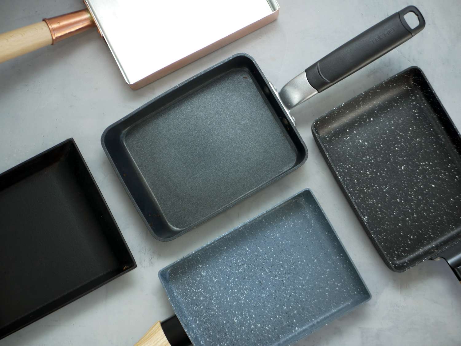 five tamagoyaki pans on a gray surface