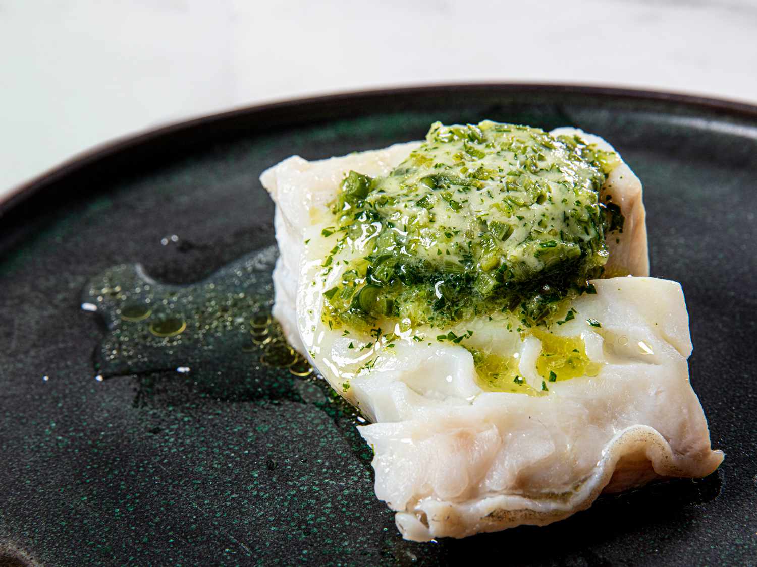 A piece of compound butter melting on a piece of steamed fish