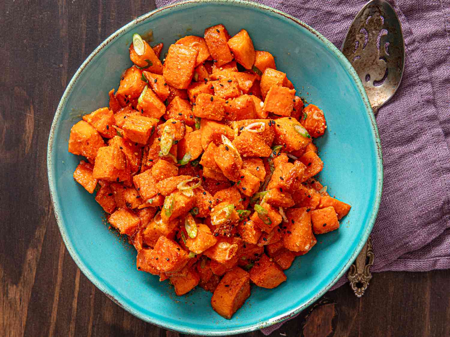 A bowl of roasted sweet potatoes with scallions.