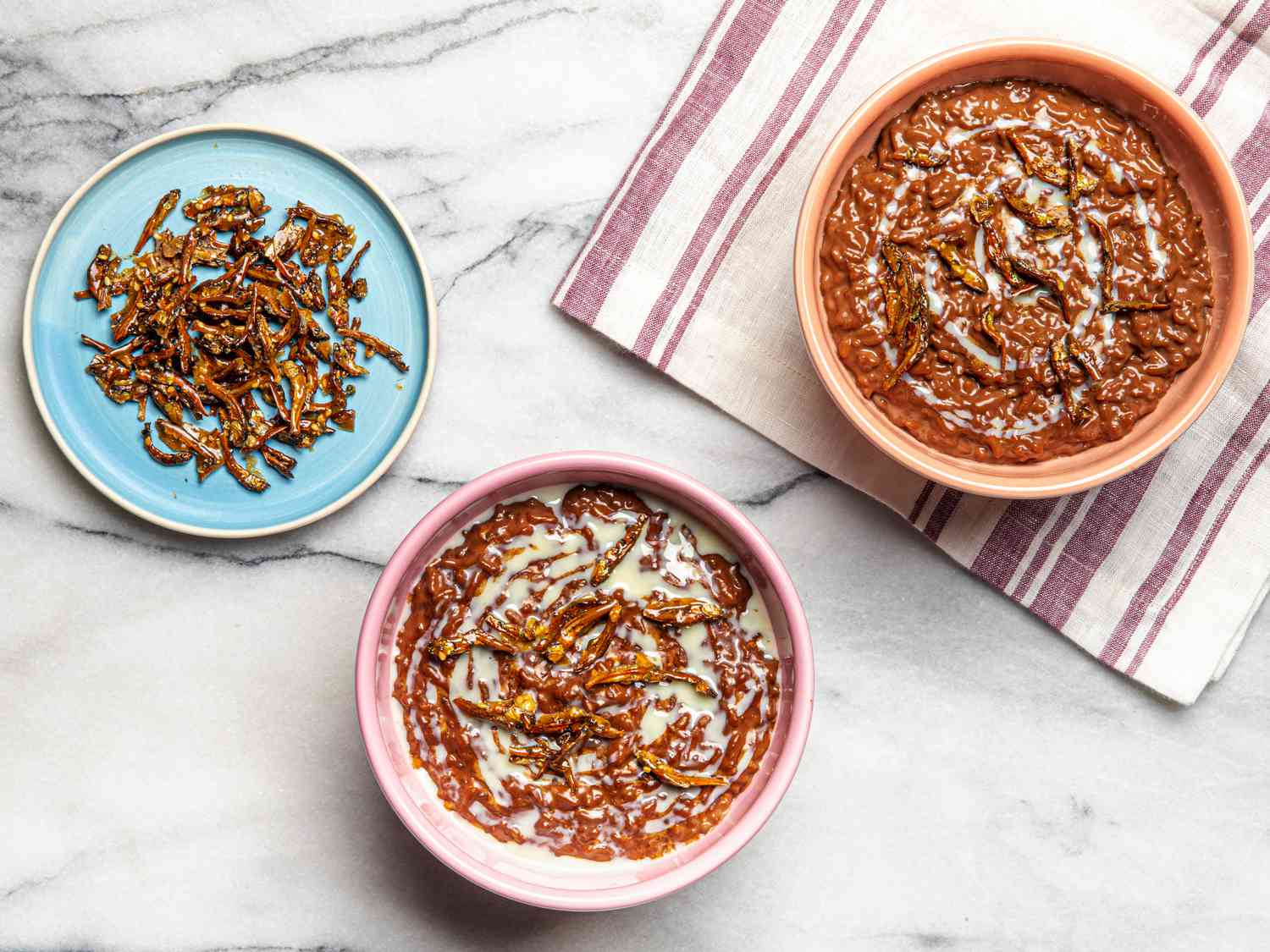 Overhead view of two bowls of Champorado and a side plate of candied anchovies