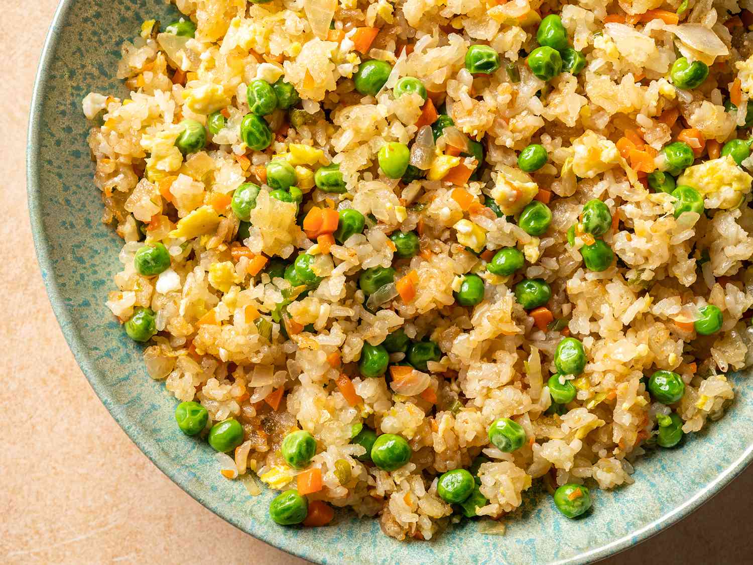 Vegetable fried rice inside a green ceramic bowl.