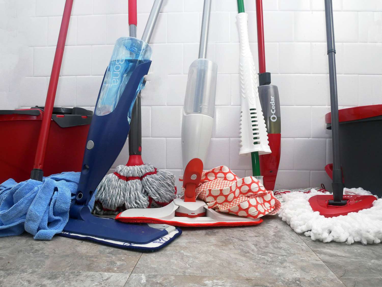 mops leaning against a white tile wall 