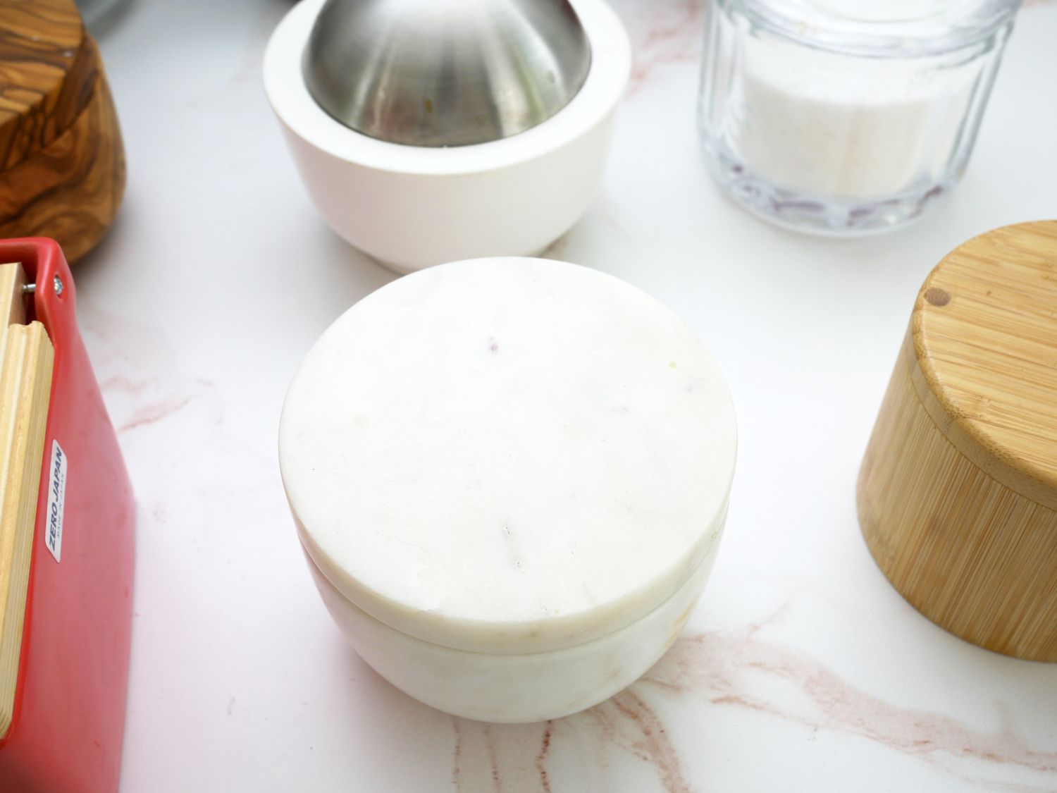 a marble salt cellar surrounded by other salt cellars on a pink and white marble countertop