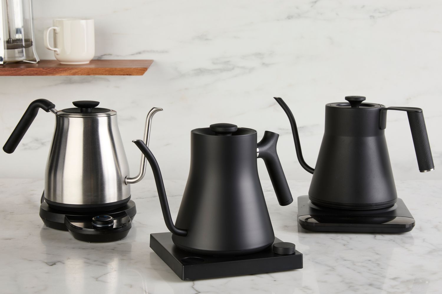 Three gooseneck kettles on a kitchen countertop.