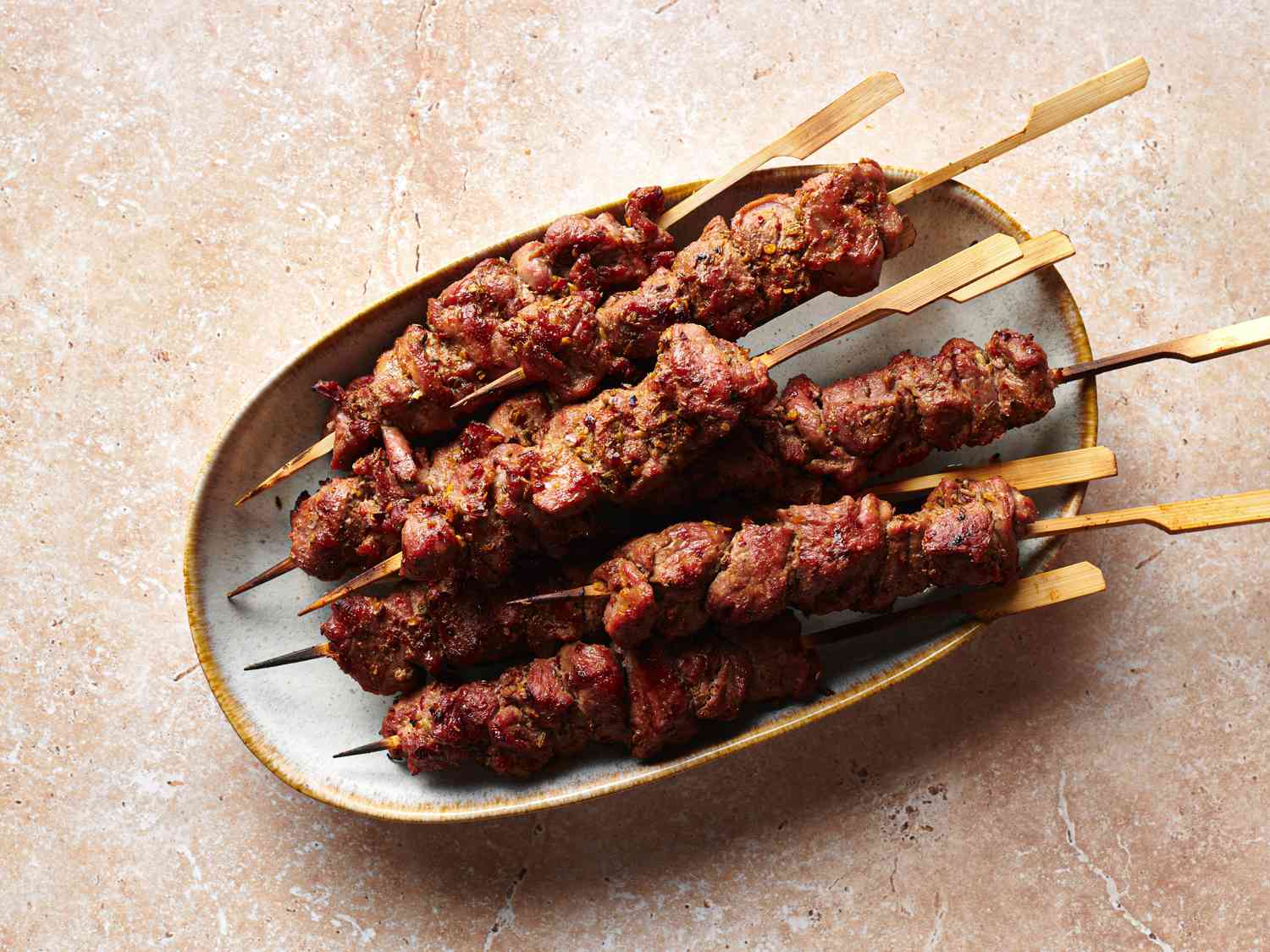 Skewers of spicy cumin lamb (yang rou chuan) on an oval platter.