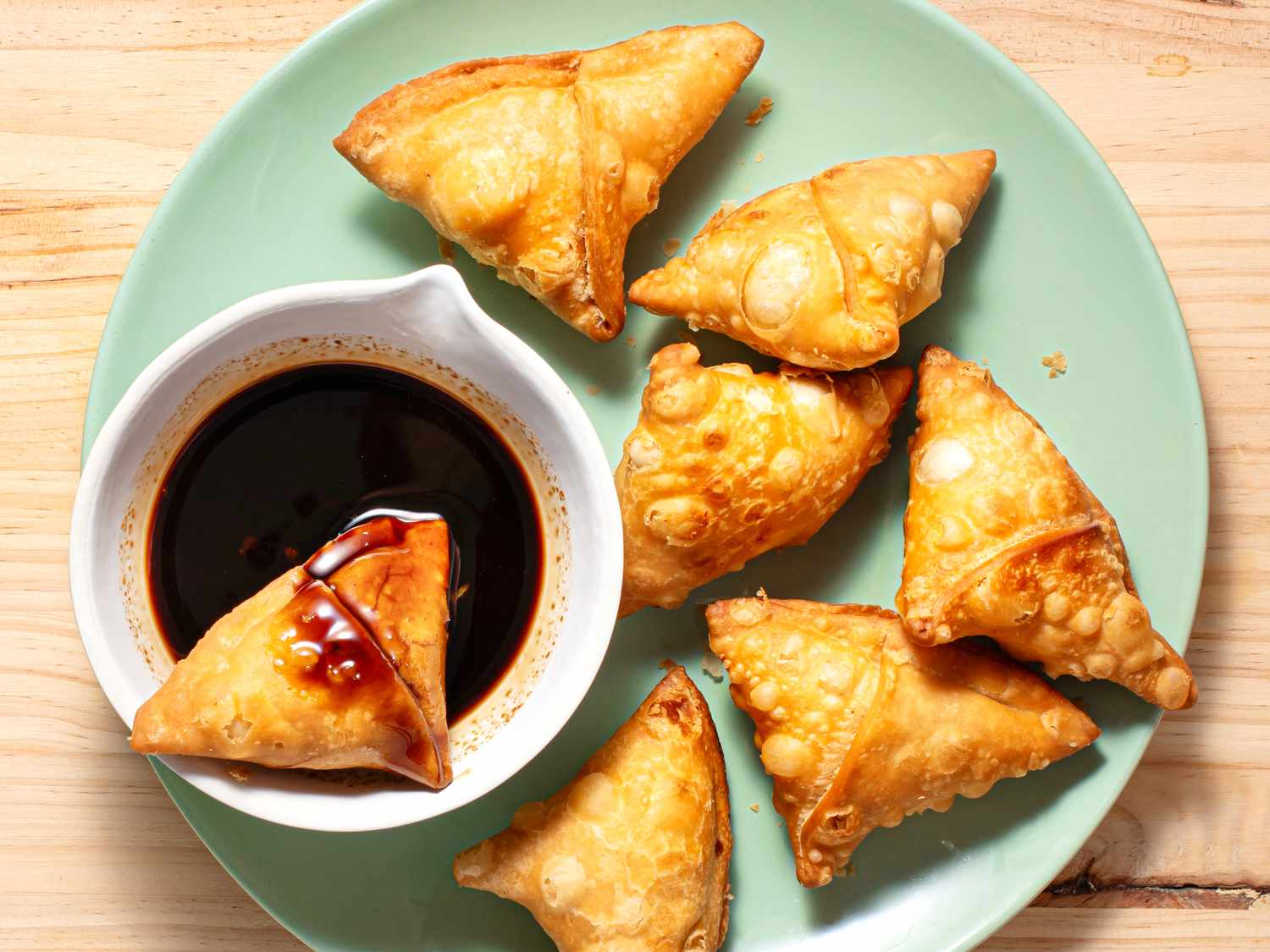 Tamarind chutney in a bowl with fried samosas.