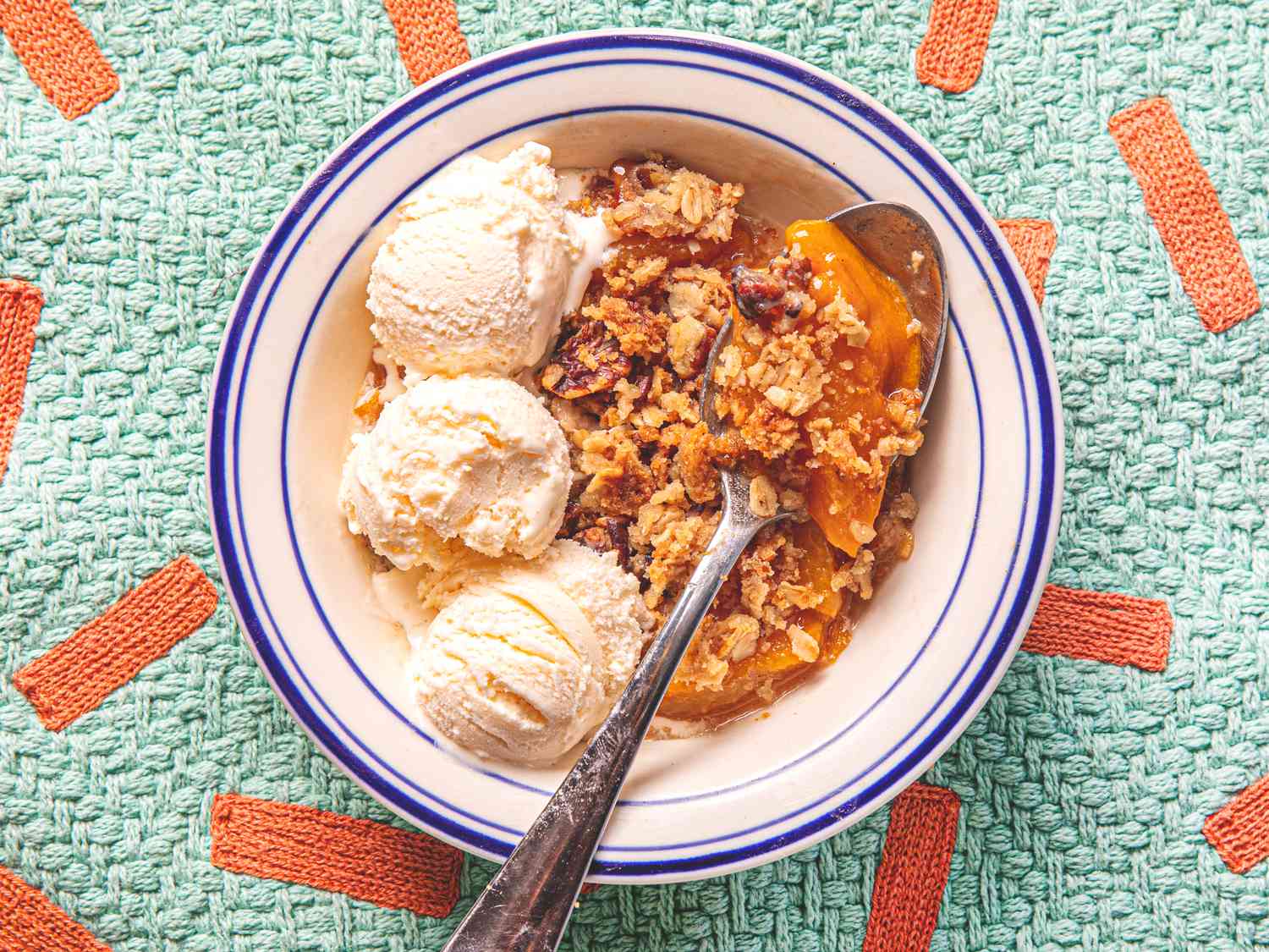 Overhead view of peach crisp served with ice cream