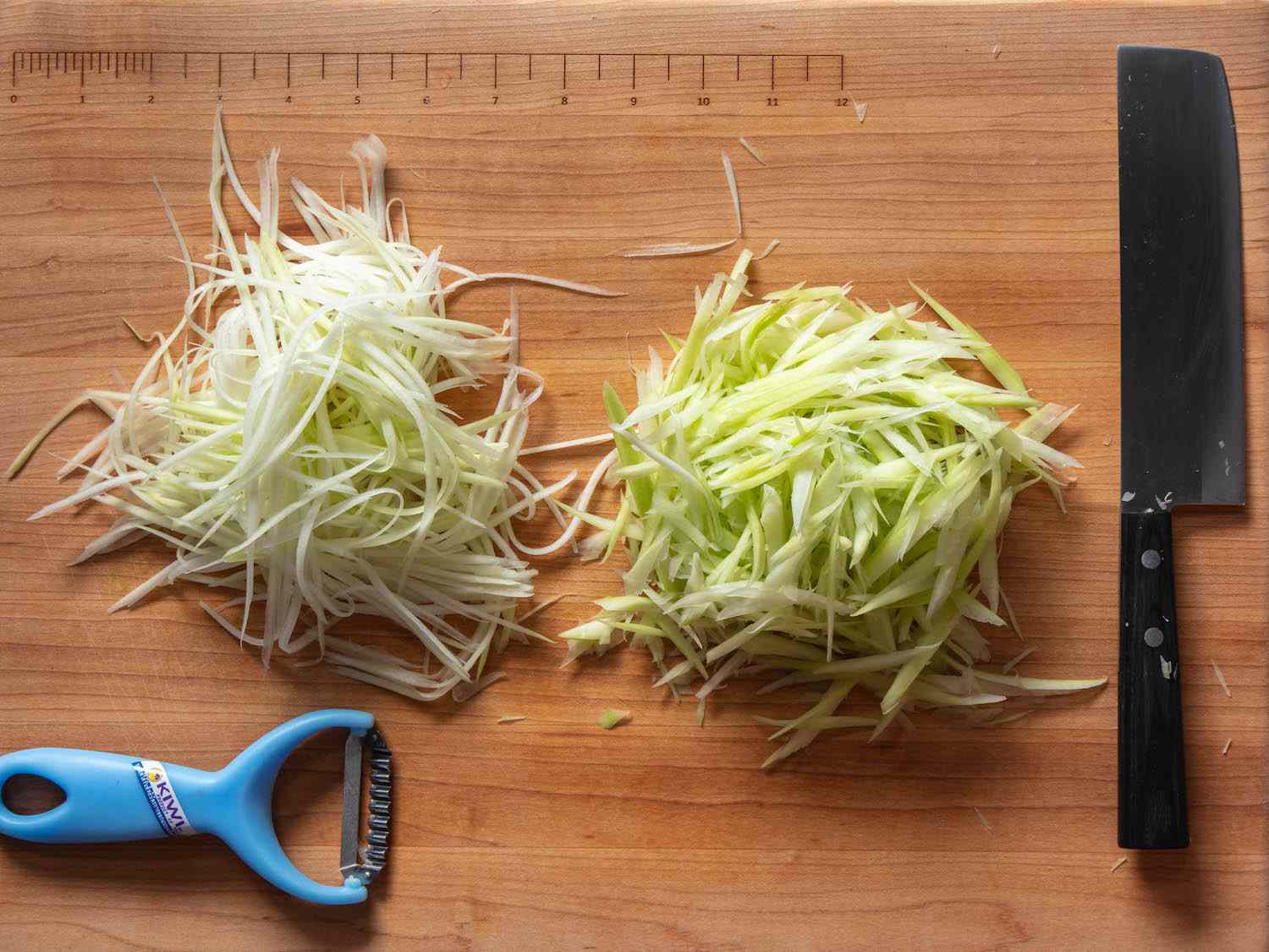 Knife-cut and peeler-shredded green papaya on a cutting board